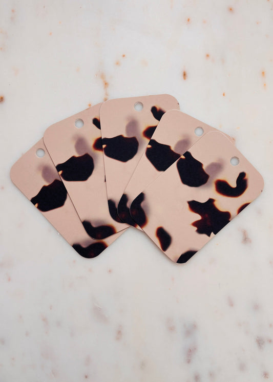 Five Tortoiseshell gift tags fanned out one on top of the other on a marble background