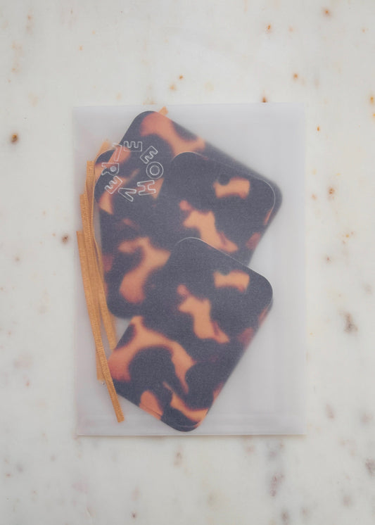 Tortoiseshell gift tags in a glassine envelope, with gold lame ribbon on a marble background